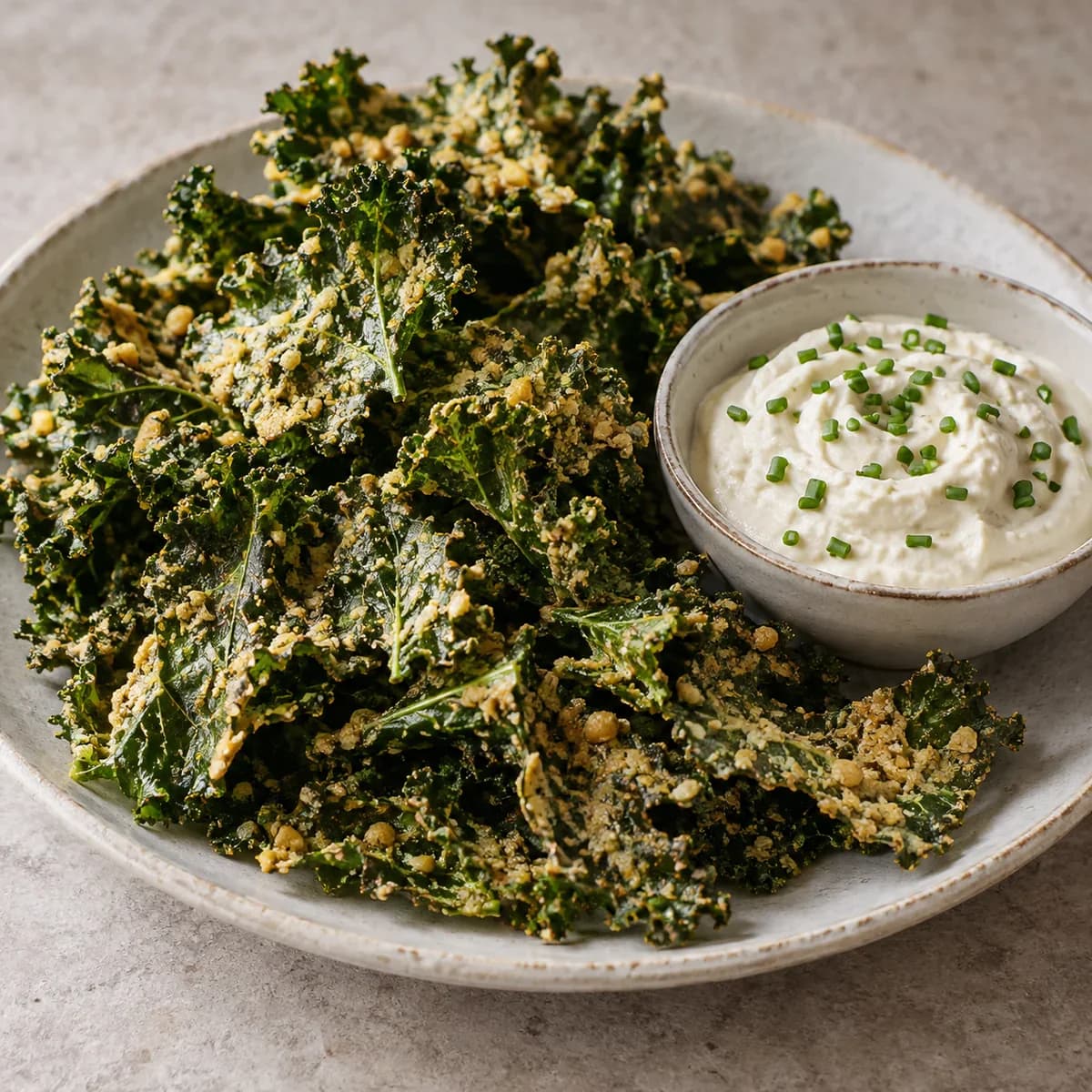 Delicate almond-coated kale crisps alongside a bowl of white lemon-chive tofu dip