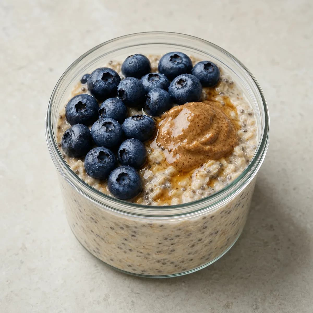 Creamy overnight oats topped with blueberries, almond butter, maple syrup, and cinnamon