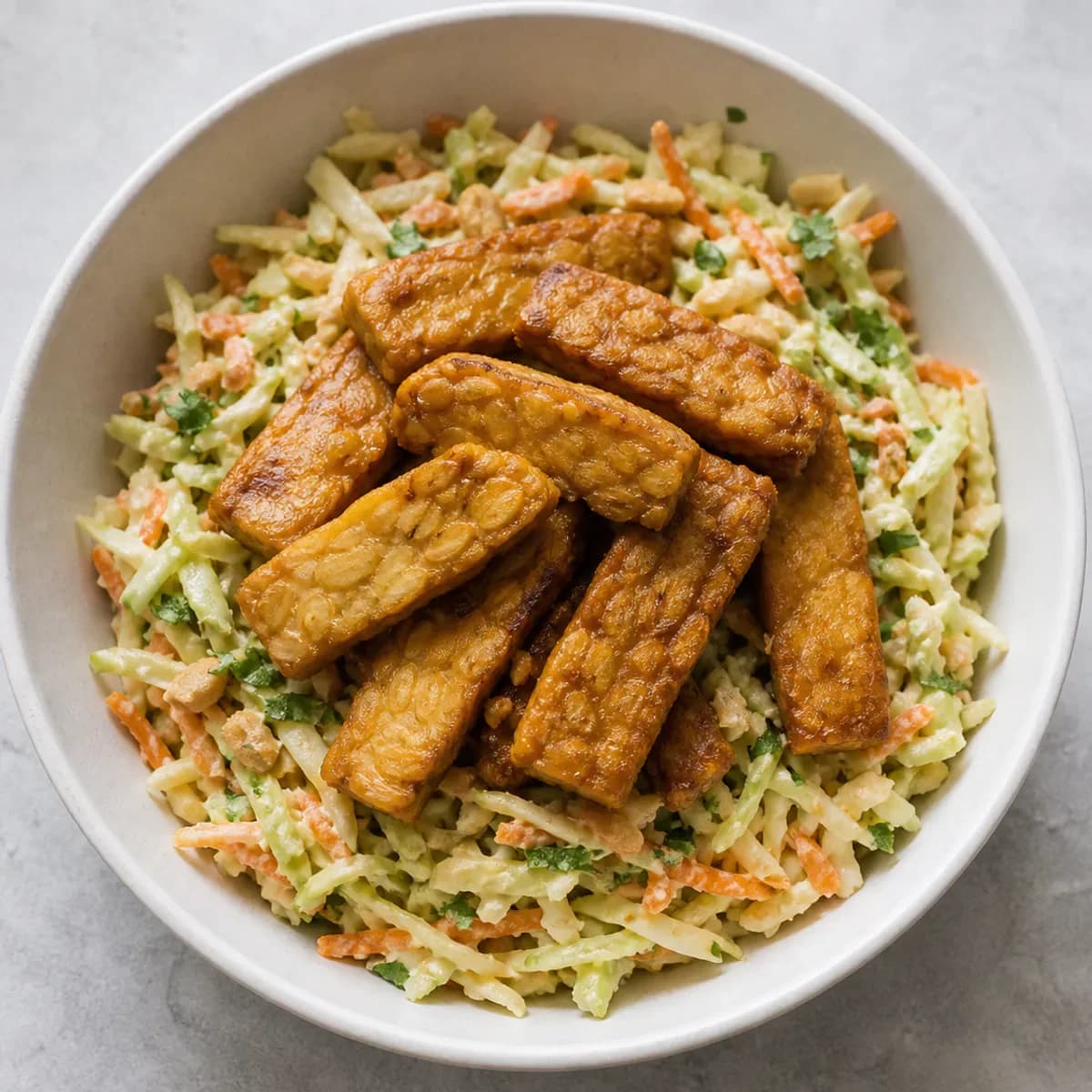 Golden tempeh over crunchy almond-lime cabbage slaw served as one complete portion